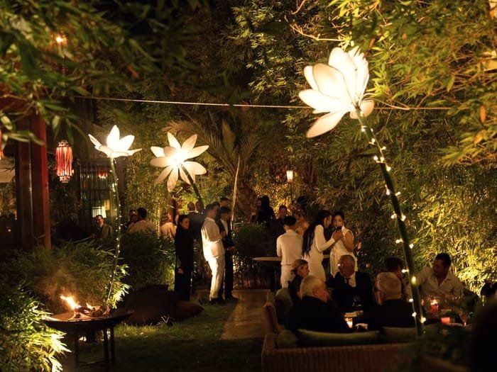 Una recepción nocturna en el jardín, iluminada por farolillos y esculturas florales luminosas.