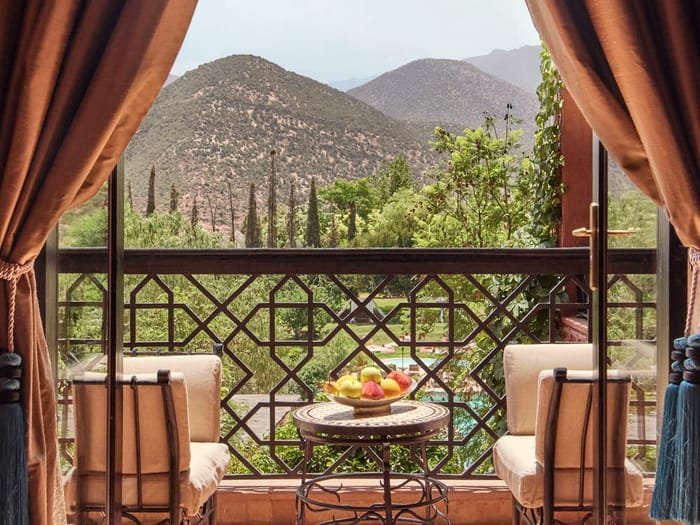 Una terraza tranquila enmarcada por cortinas, con vistas a las montañas del Atlas.